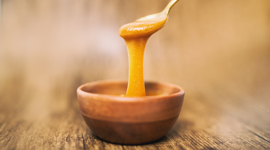 Raw Honey drizzling in to a wooden bowl