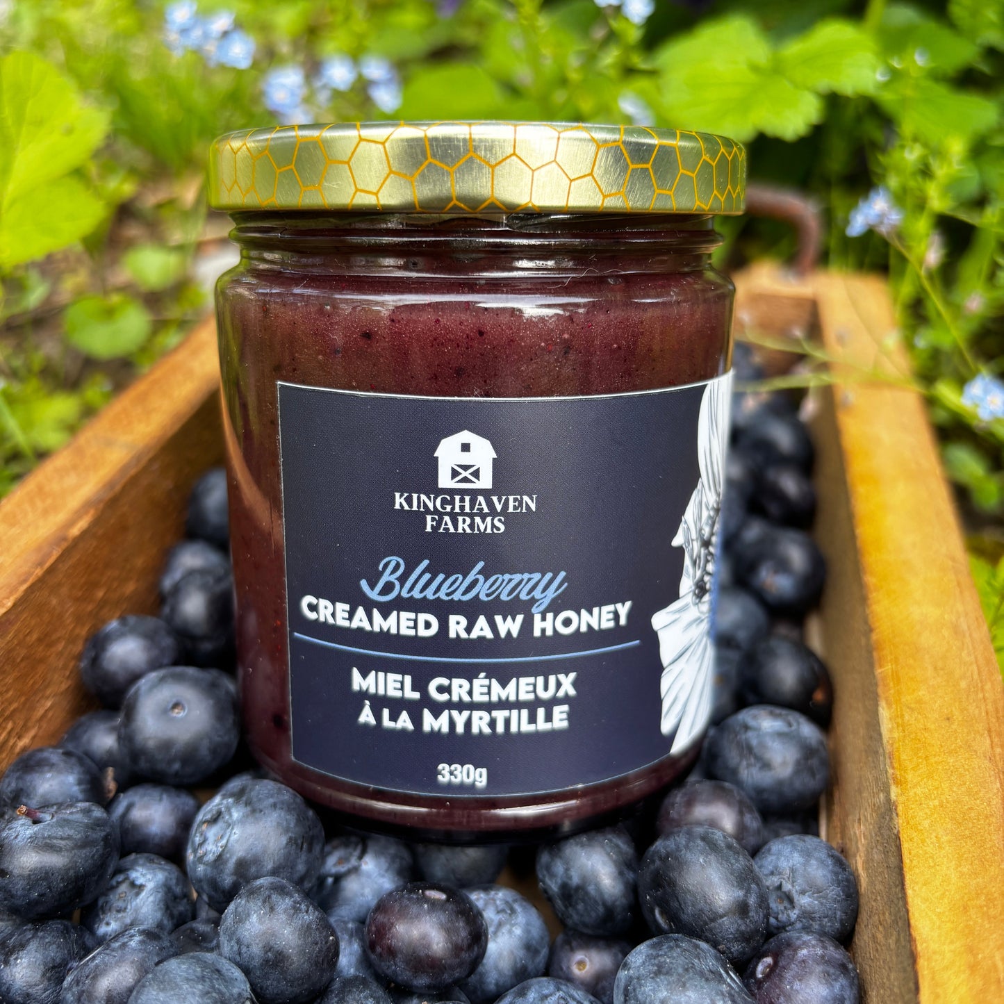 Jar of blueberry honey surrounded by blueberries with a natural background